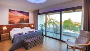 Een hotelkamer met een bed, twee bedlampjes, een groot raam met uitzicht, een balkon met een tafel en stoelen, en een plafondlamp.
