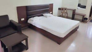Una habitación de hotel con una cama individual, un escritorio, una silla y una mesita.