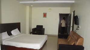 Habitación de hotel con cama, una silla, sofá, televisor y puerta.