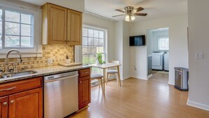 A kitchen with wooden cabinets, a dishwasher, a countertop with a sink, and a ceiling fan. - Sandusky Adventure Hub: Patios, Grill + Yard! (Sandusky)