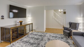 A living room with a flat-screen TV, a grey sofa, a wooden coffee table, and a grey shaggy rug. - Sandusky Adventure Hub: Patios, Grill + Yard! (Sandusky)