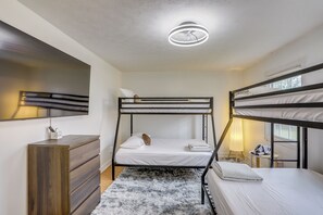 Une chambre avec un lit superposé, un bureau, un miroir et un luminaire au plafond.