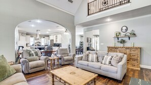 Un vaste salon comprenant un coin repas, une cuisine à l’arrière-plan et un escalier menant à l’étage supérieur.