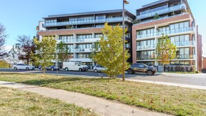 A multi-story building with a modern architectural design, featuring large windows and a flat roof. - Griffith Apartment | Prime Location+Courtyard+Gym (Griffith)