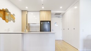A modern kitchen with a central island, wooden cabinets, and a built-in refrigerator. - Griffith Apartment | Prime Location+Courtyard+Gym (Griffith)