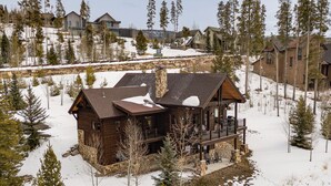 Una cabaña de madera con base de piedra, un balcón y un paisaje cubierto de nieve.