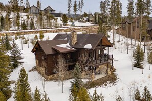 Eine Holzhütte mit Steinuntergrund, einem Balkon und einer verschneiten Landschaft.