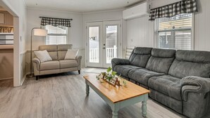 Ein Wohnzimmer mit einem beigen Sofa, einem dunkelgrauen Sofa, einem Holztisch und einer Stehlampe.
