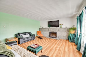 A living room with a fireplace, a sofa, a coffee table, and a television mounted on the wall.