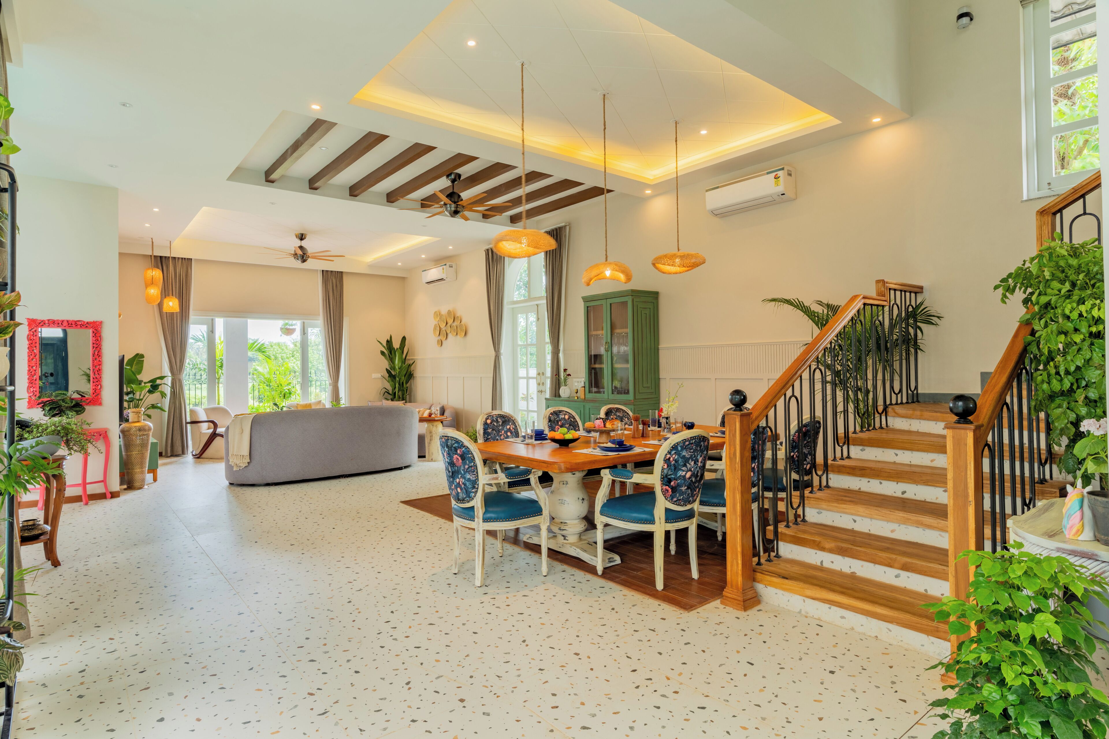 A spacious living area with a dining table, chairs, and a staircase with wooden railings.