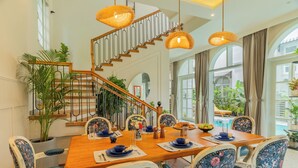 Un comedor con una mesa de madera, sillas con estampado floral y una escalera con barandilla.