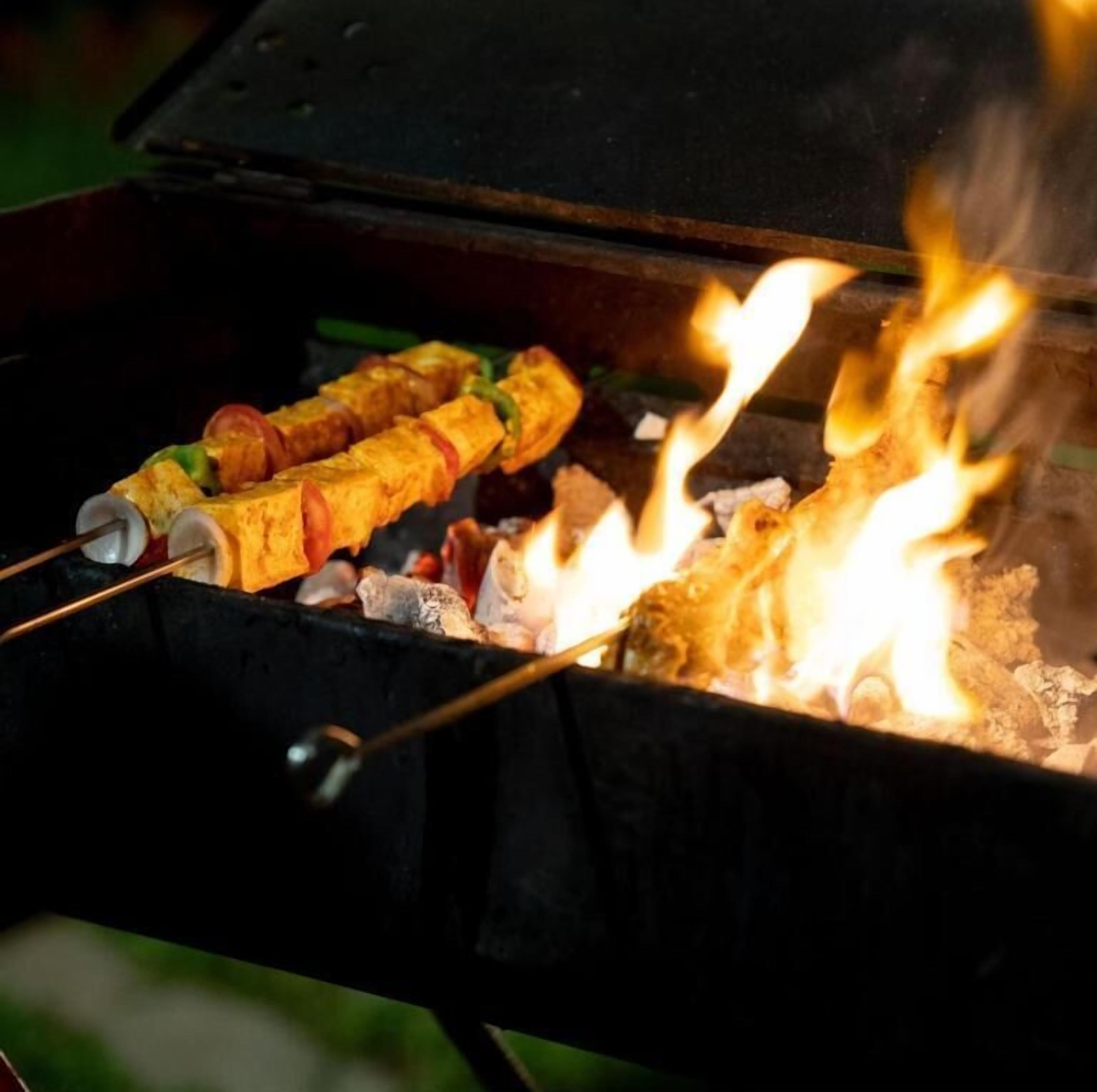 Egy grill, amelyen nyársra tűzött ételeket készítenek nyílt láng felett.