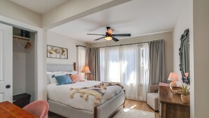 Ein Schlafzimmer mit Bett, Nachttisch, Stuhl und Deckenventilator.