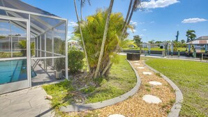 Un bâtiment moderne doté d’une façade en verre, d’une piscine et d’un jardin paysager agrémenté de palmiers.