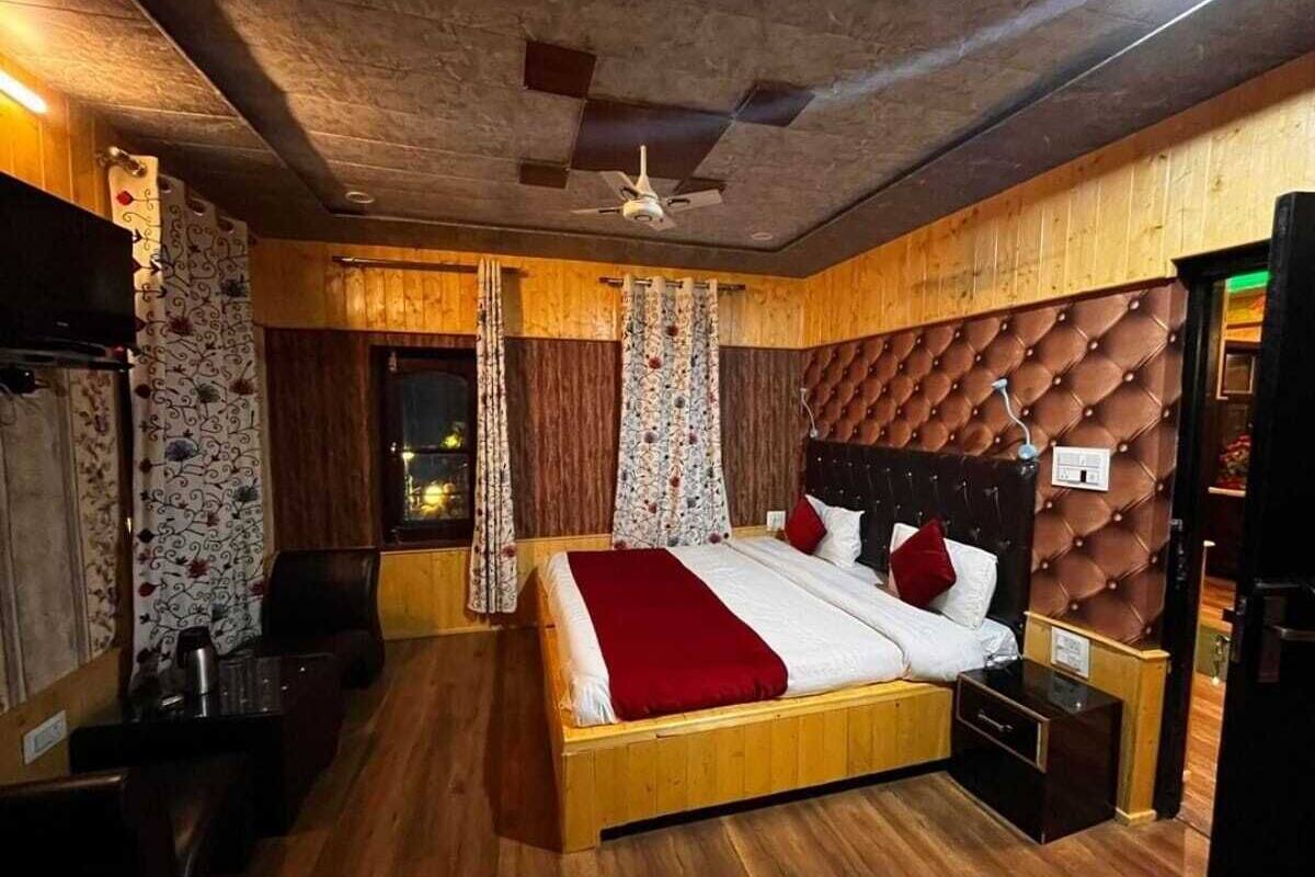 Quarto com cama de madeira, ventoinha no teto e janela com cortinas.