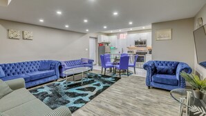 Un salon moderne avec un canapé bleu, une table à manger et des chaises, et une cuisine en arrière-plan.