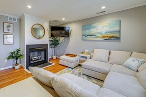 Un salon avec une cheminée, un grand canapé, un téléviseur et un tableau accroché au mur.