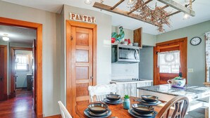 A kitchen with a wooden door labeled 'PANTRY,' a white chair, and a dining table set with plates and cutlery. - Half-Mi to Boat Ramp! Gasconade Country Cottage (Gasconade)