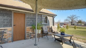 A covered patio area with a stone building, a wooden door, a window, and outdoor furniture. - Half-Mi to Boat Ramp! Gasconade Country Cottage (Gasconade)