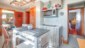A kitchen with a granite countertop, wooden cabinets, a microwave, and a hanging light fixture. - Half-Mi to Boat Ramp! Gasconade Country Cottage (Gasconade)