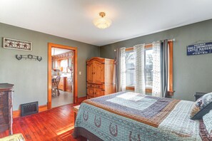 A bedroom with a large bed, wooden wardrobe, and a window with curtains.