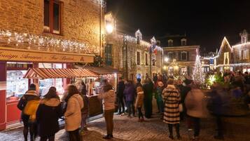 Une rue pavée, éclairée la nuit, où des gens se sont rassemblés autour d’un étal de nourriture, des bâtiments historiques illuminés et une enseigne indiquant « Antiqua ».