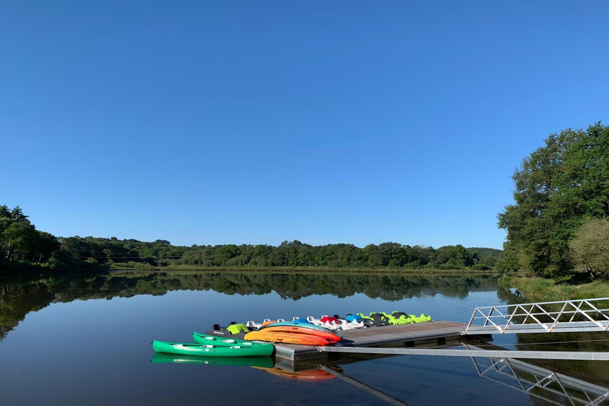 Un lago tranquilo con un muelle y kayaks.