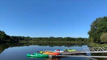 A calm lake with a dock and kayaks.
