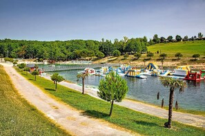 Un parque junto al río con un sendero para caminar, barcos y toboganes de agua.