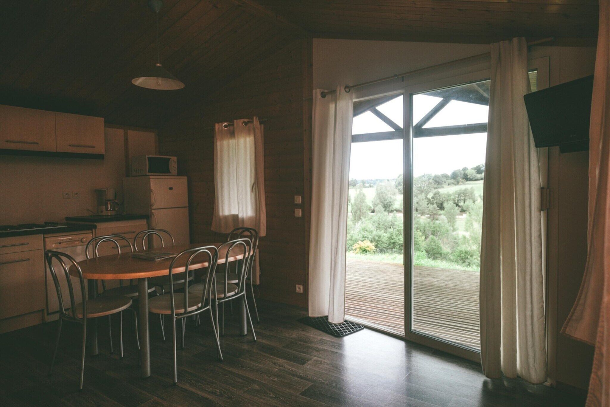 A kitchen with a dining table and chairs, a microwave, and a view through a sliding glass door to an outdoor deck.