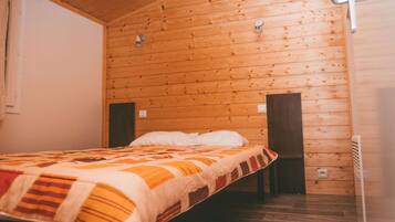Una habitación con paneles de madera, una cama, dos lámparas de pared y un ventanal.