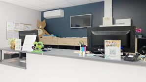 A reception desk with a large animal mascot, a flat-screen TV, and a sign with a QR code.