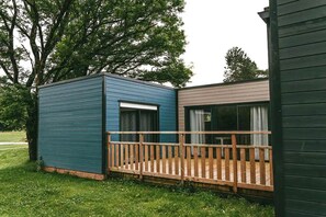 Een klein huisje met een houten terras en een raam.
