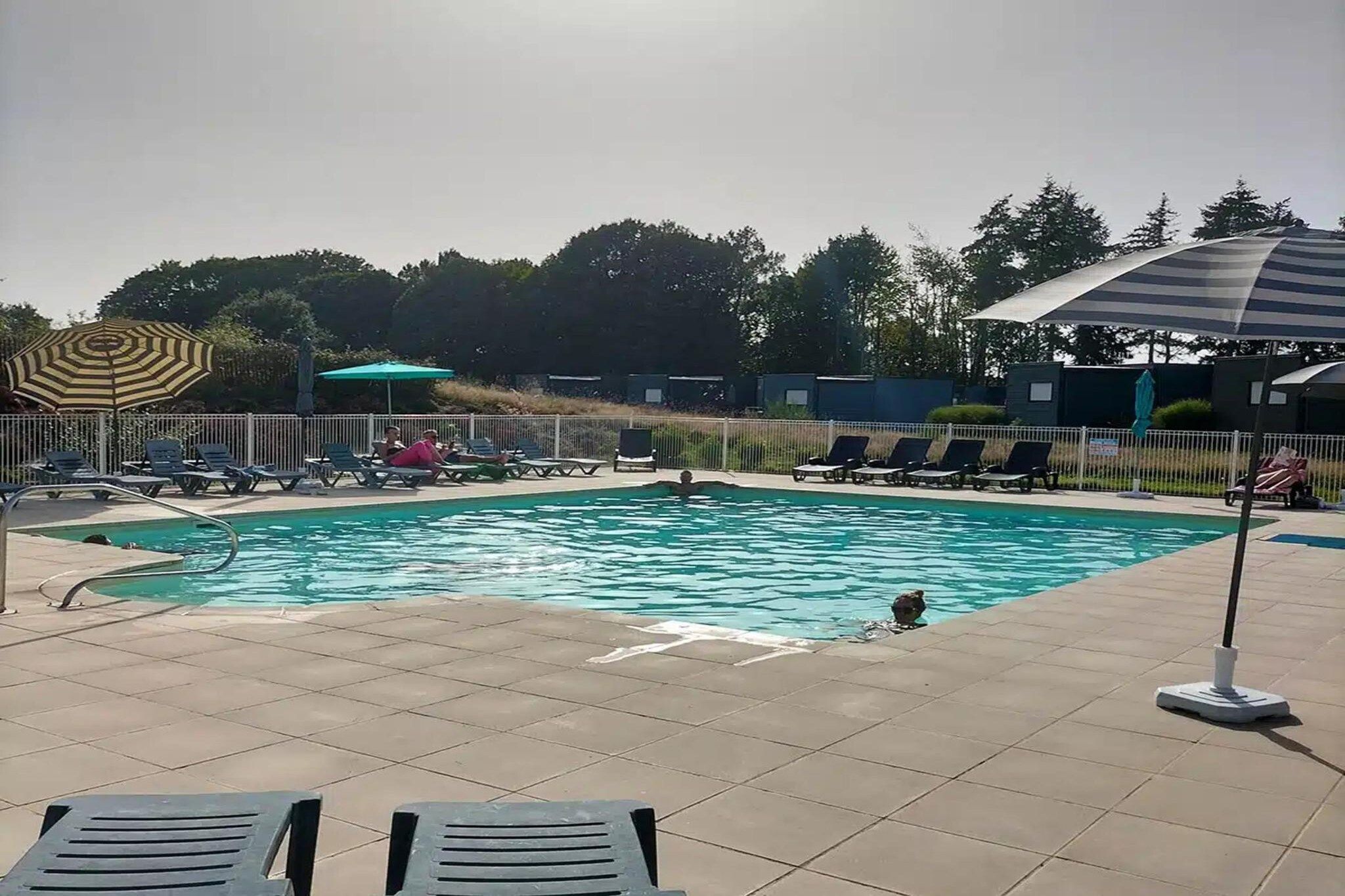 Una piscina con sillas de descanso y sombrillas.
