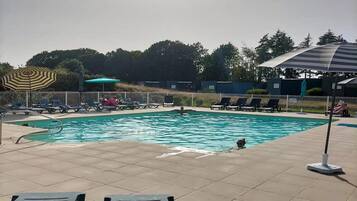 Una piscina con sillas de descanso y sombrillas.