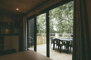 Een kamer met een schuifglazen deur die uitkomt op een terras met een tafel en stoelen.