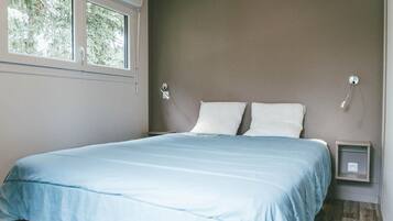 Un dormitorio con una cama, dos lámparas de noche, una ventana y una mesita de noche.