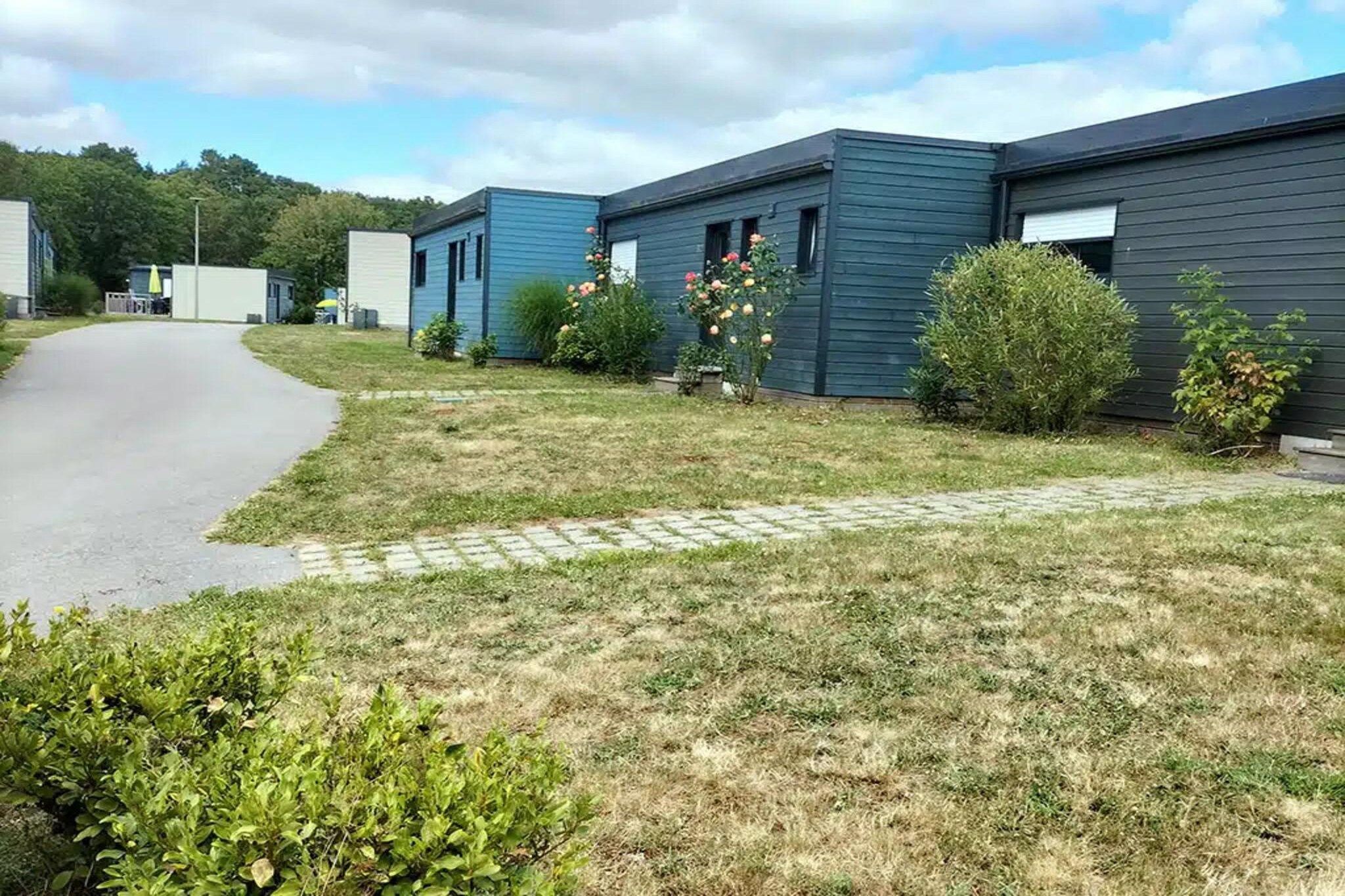 A row of modern, single-story buildings with a paved driveway leading to a grassy area.