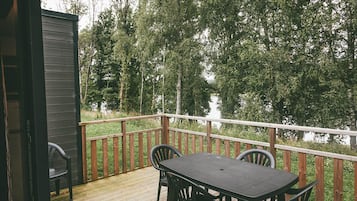 A wooden deck with a table and chairs, overlooking a forested area.