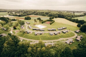 Un quartier résidentiel comprenant plusieurs maisons, une place centrale et de vastes champs verdoyants environnants.