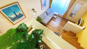 A living room with a sofa, a small table, a plant, and a staircase. - A quiet residential area that blends in with the local community ｜ Close to LaLaport Fukuoka ｜ Close to Fukuoka Airport ｜ Refreshing space (Morooka Hakata-ku Fukuoka city)