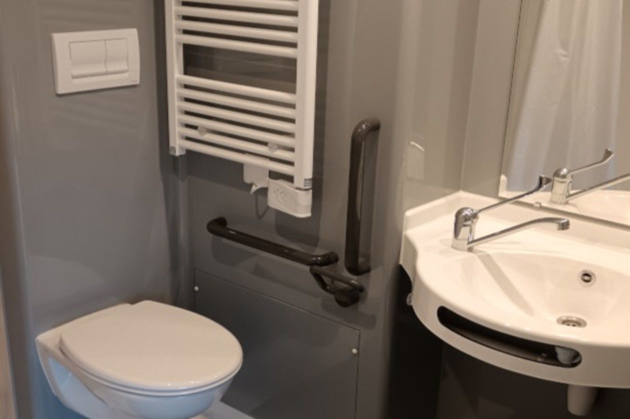Een badkamer met toilet, wastafel en handdoekhouder.