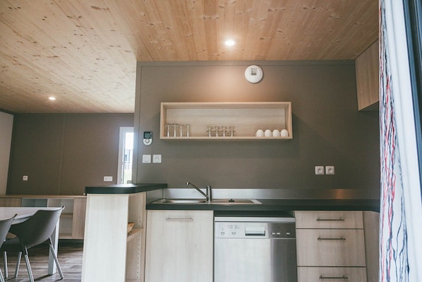 A modern kitchen with wooden cabinets, a built-in dishwasher, and a countertop with a sink.
