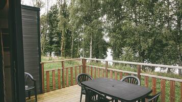 Eine Holzterrasse mit Tisch und Stühlen, mit Blick auf ein bewaldetes Gebiet.
