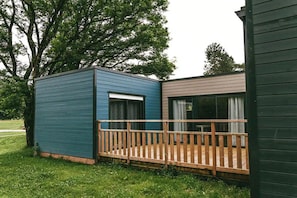 A two-story cabin with a deck, a window, and a door.