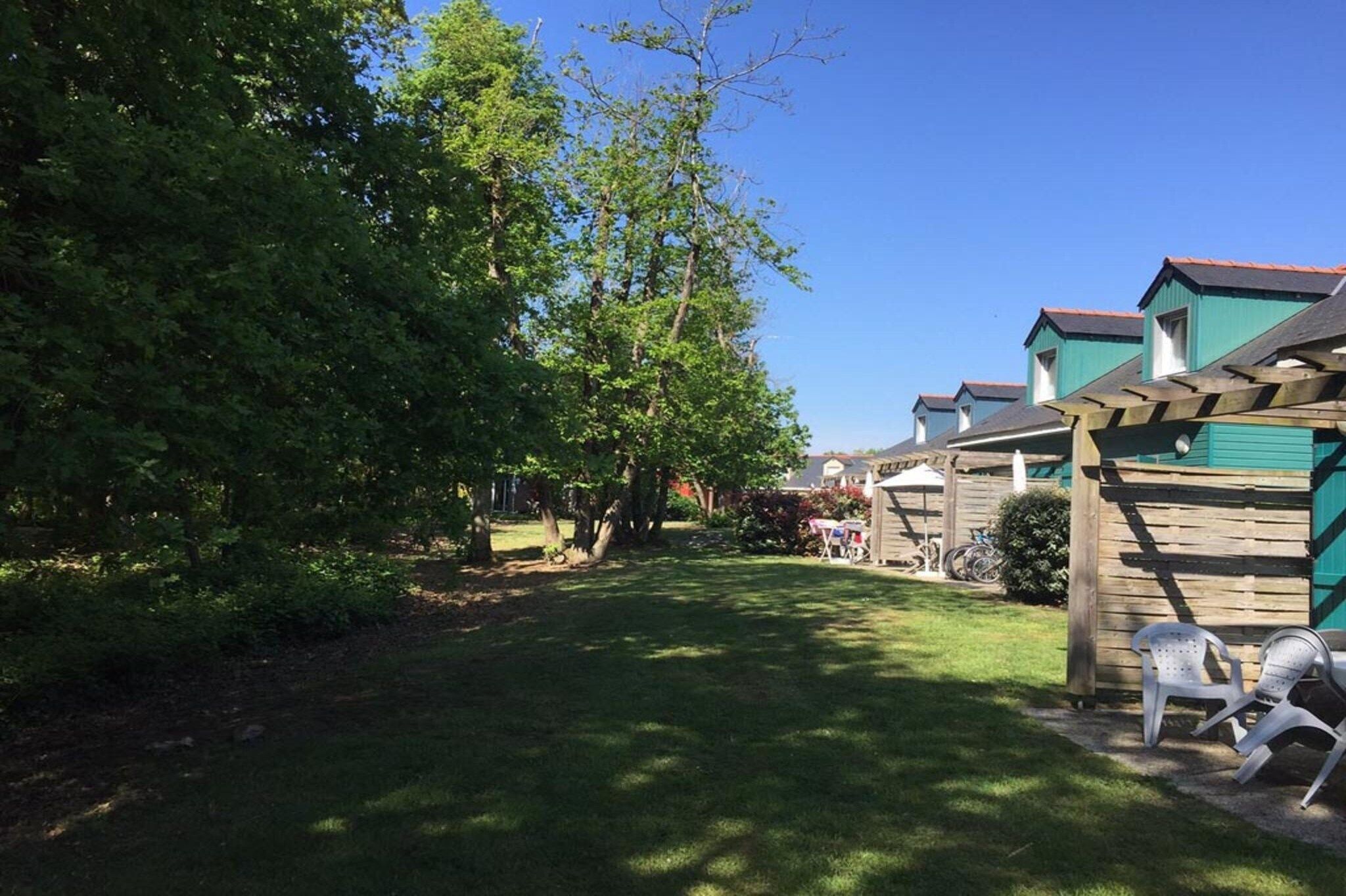 Patio trasero residencial con una pérgola de madera, césped y una hilera de casas al fondo.