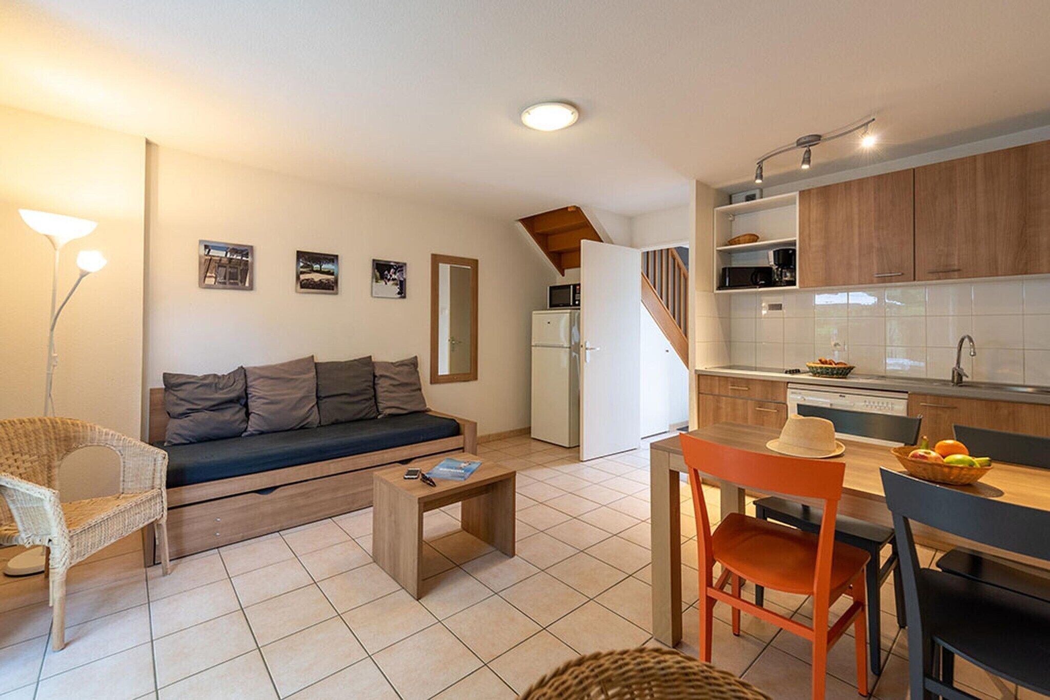 A compact living space with a sofa, a dining table, a kitchen area, and a staircase.