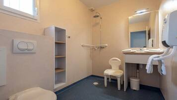 Ein Badezimmer mit Toilette, Dusche, Waschbecken und einem Stuhl.