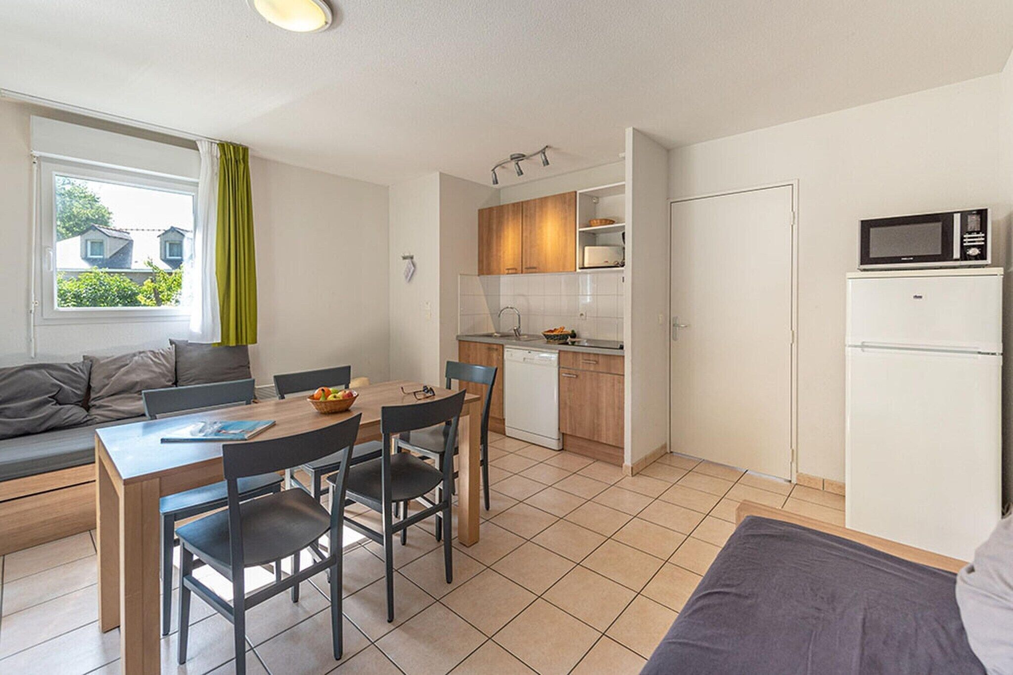 A compact kitchen with a dining area, a microwave, and a refrigerator.