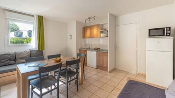 A compact kitchen with a dining area, a microwave, and a refrigerator.